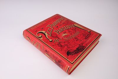 un vieux livre rouge posé sur une table blanche
