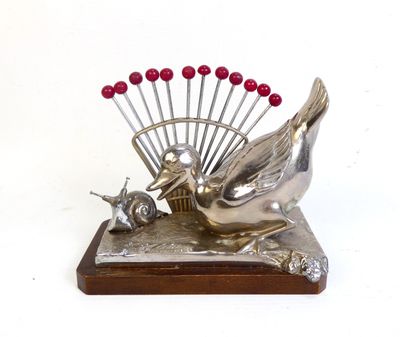 une sculpture en argent représentant un oiseau et un éventail posée sur une table