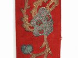 red and gold embroidered ribbon with flowers and leaves on a white background