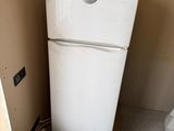 a white refrigerator sitting next to a bed in a room