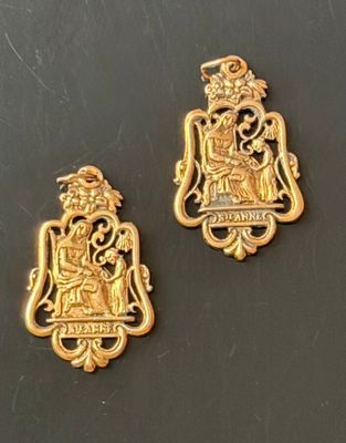 pair of gold plated pendants depicting a coat of arms and a crown