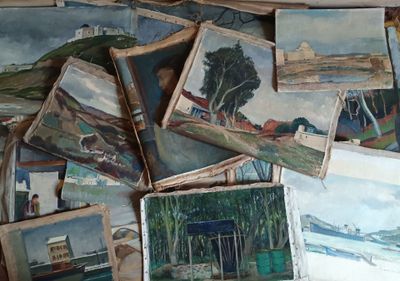 une pile de tableaux posés par terre dans une pièce