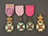 quatre médailles sont exposées sur une table, ornées d'un ruban rose