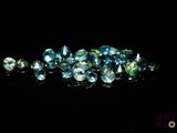 un tas de pierres précieuses bleues et vertes sur une surface noire