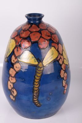 un vase bleu sur lequel est peinte une libellule