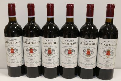 six bouteilles de vin rouge sont alignées sur une surface blanche