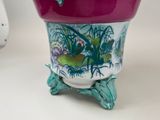 a purple vase with a bird on it sitting on a table