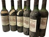 six bouteilles de vin sont alignées sur une surface blanche