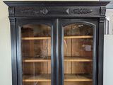 a black cabinet with two glass doors and a clock on top of it