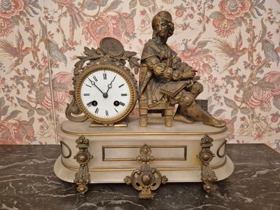 une statue représentant un homme assis sur une table, avec une horloge devant lui