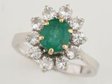 a close up of a ring with a green stone surrounded by white diamonds