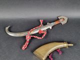 a close up of a knife on a black surface with a red rope