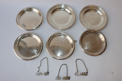six assiettes argentées et un cintre en fil de fer posés sur une surface blanche