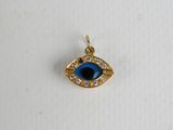 a gold and blue evil eye charm on a white surface