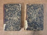 two old books sitting on top of a table next to each other