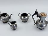 three silver teapots and a coffee pot on a table