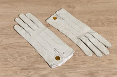 two pairs of white gloves sitting on top of a wooden table