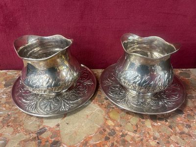 une paire de vases plaqués argent posés sur une table avec un fond rouge