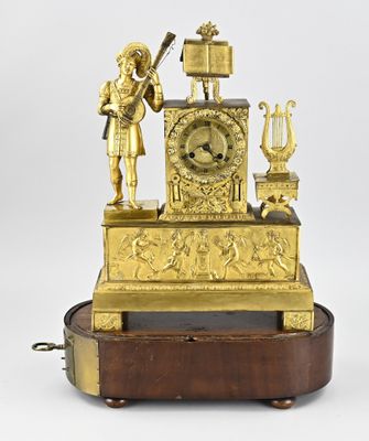a gold clock on a wooden stand with a statue of a man