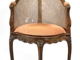 une image représentant une chaise avec un dossier en rotin et un coussin orange
