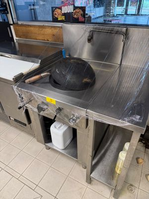 un plan de travail en acier inoxydable sur lequel est posée une poêle, dans une cuisine professionnelle