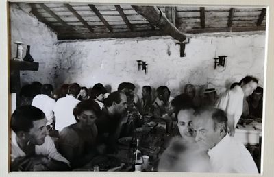 une photo en noir et blanc montrant un groupe de personnes assises à une table