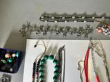 many different types of necklaces and bracelets laid out on a table