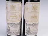 two bottles of red wine sitting next to each other on a table