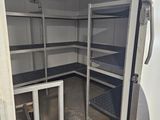 an open door to a room with shelves and a fan