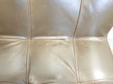 a close up of a leather couch with a cat on it