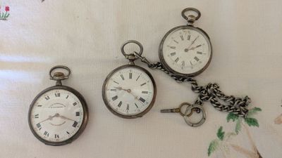 three different types of pocket watches sitting on a table