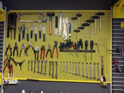 a yellow pegboard with many tools hanging on it