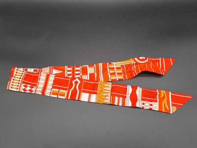une cravate orange et blanche accrochée à un mur gris