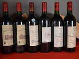 six bottles of red wine are lined up on a table