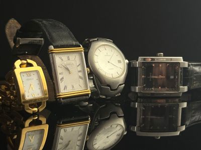 several watches are sitting on a black surface with a black background