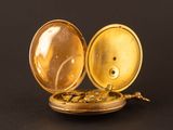a gold pocket watch sitting on a black surface