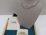 un collier et des boucles d'oreilles présentés sur un plateau, accompagnés d'un petit sac