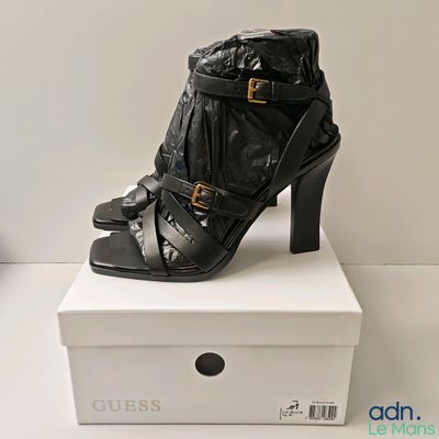 une paire de chaussures noires à talons hauts posée sur une boîte blanche