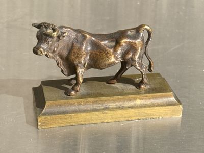 statue en bronze représentant un taureau, posée sur un socle en bois, elle-même posée sur une table