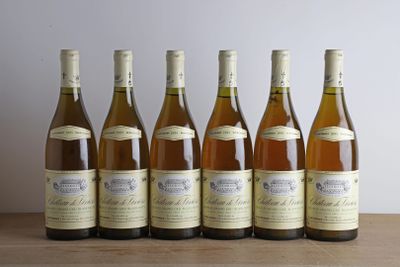 six bouteilles de vin sont alignées sur une table en bois