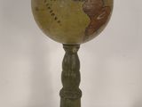 an old globe on a pedestal with a white background