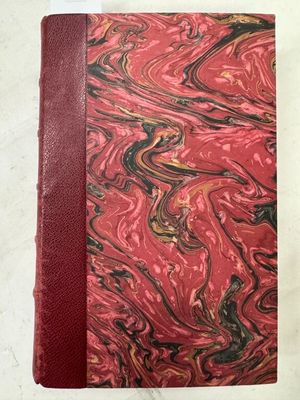 un cahier marbré rouge et noir posé sur une table blanche