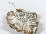 silver leaf shaped dish with a hook on a white surface