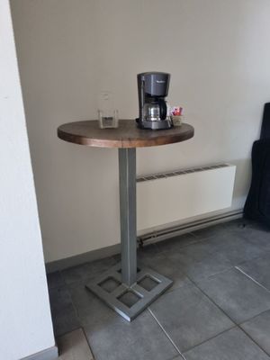 une petite table sur laquelle se trouve une cafetière, dans un coin de la pièce