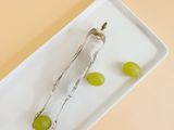 a white plate with grapes and a spoon on it