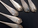 five silver spoons are arranged in a row on a black surface
