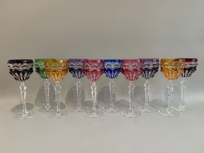 six verres à vin colorés alignés en rang sur une surface blanche