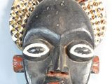 an african mask hanging on a wall with a white background