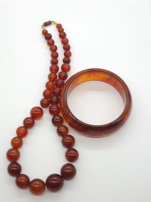 two pieces of jewelry on a white surface with a ring