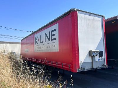 un camion rouge et blanc garé à côté d'un immeuble